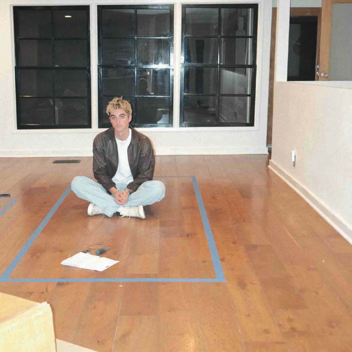 Elijah Woods' 'We Should Stick Together' (Acoustic) cover art features him sitting on the floor of an empty room.